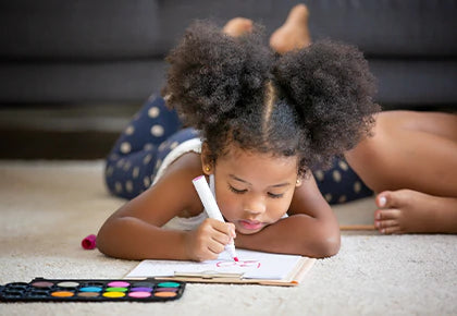 Little African girl is working on some activity mats on the floor. 