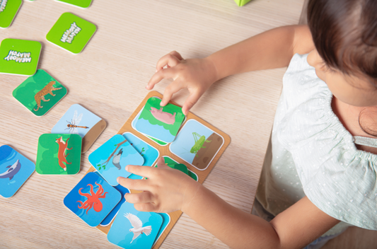 Little girl playing Memory Match by Skillmatics on a wooden table