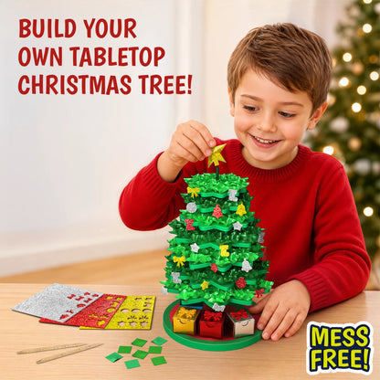 Child smiling while building a tabletop Christmas tree with Skillmatics Poke-In Art. The child holds a golden star above the decorated green fabric tree, with glitter ornaments, mini gift boxes, fabric squares and poke-in sticks on a wooden table; a blurred Christmas tree appears in the background.