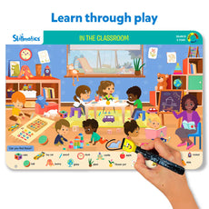 Skillmatics educational game board with children in a classroom scene and a hand holding a marker.