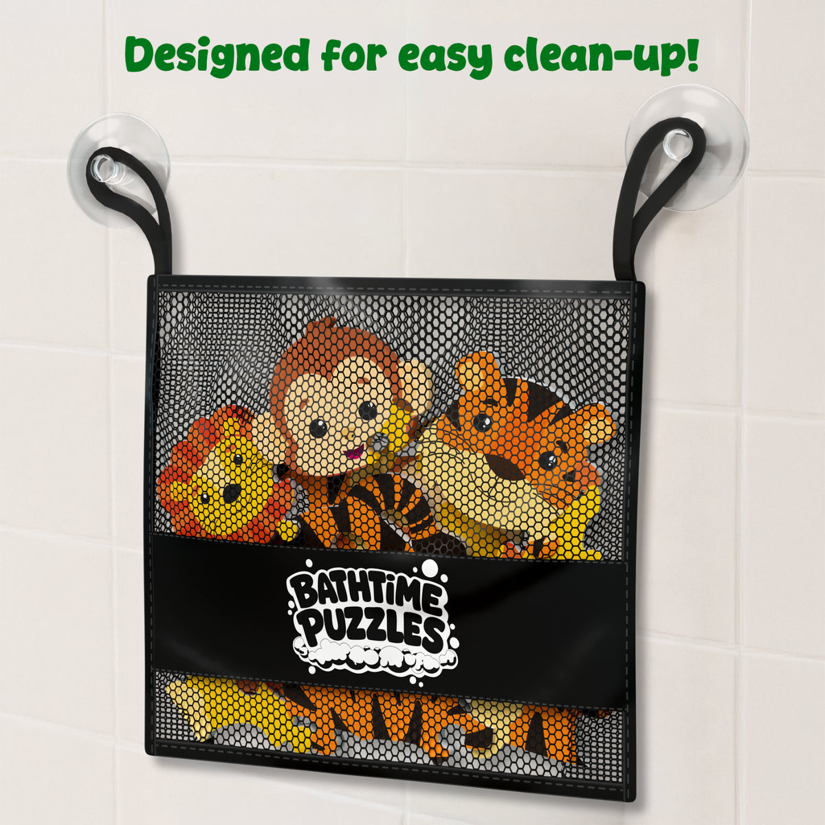 Black mesh storage bag labeled “Bathtime Puzzles” hangs from a bathroom wall hook against white tiles. Inside the bag are colorful foam animal puzzle pieces, including a lion, monkey, and tiger. Green text at the top reads “Designed for easy clean-up!” highlighting convenient storage after bath play.