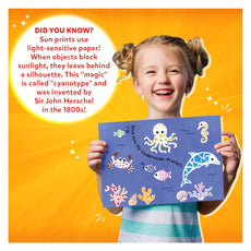 Smiling girl holding a cyanotype sun print from Magical Sun Art Animals Kit